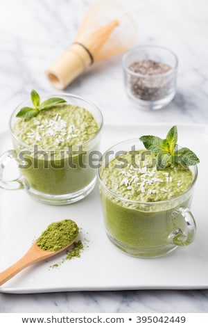 Foto stock: Matcha Green Tea Chia Seed Pudding Dessert With Fresh Mint And Coconut On A White Stone Background