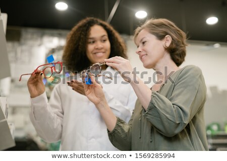 Foto stock: Young Competent Mixed Race Consultant Showing Pair Of Eyeglasses To Female Buyer