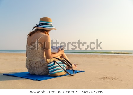 Сток-фото: Woman Sitting On Beach Holding Hat
