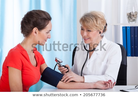 Foto d'archivio: Young Doctor Checking Blood Pressure Of Female Patient