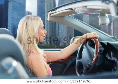 [[stock_photo]]: Woman Driving Convertible Car Over Singapore City