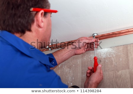 Foto stock: Plumber Fitting Copper Pipes To A Wall