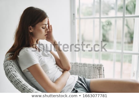 Foto stock: Portrait Of A Tired Young Woman Sitting On Her Bed