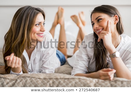 Foto stock: Two Beautiful Girls Talking And Smiling While Lying On A Bed