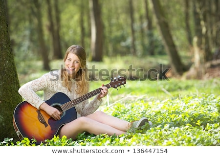 Foto stock: Blond Woman Sitting And Playing Guitar