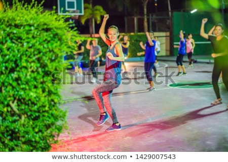 Foto stock: Young Woman On A Group Workout On The Basketball Court In The Evening