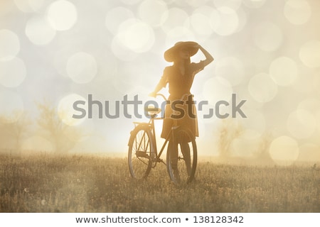 Stok fotoğraf: Girl On A Bike In The Countryside In Sunrise Time