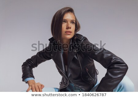 Foto stock: Seated Fashion Model Wearing Leather Jacket And Looking Away