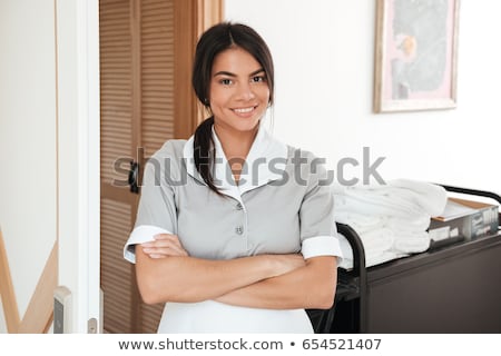 Zdjęcia stock: Smiling Housekeeping Worker Standing With Bedclothes Linen In Cart