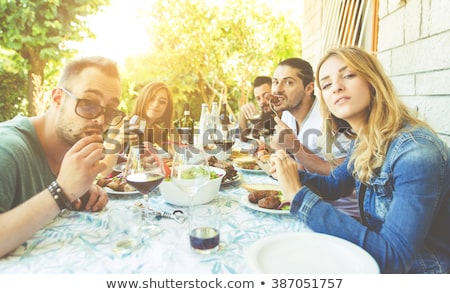 Foto stock: Group Of Young People Sitting By The Table And Drinking Red Wine