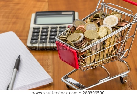 Imagine de stoc: Shopping Cart Filled With Coins On A Wooden Desk