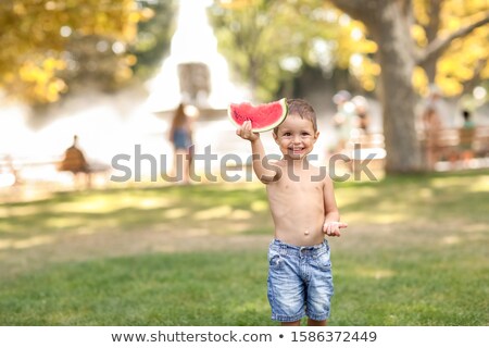 Stock photo: Child Outdoor In A Public Park On The Grass Running With A Slice Of Watermelon