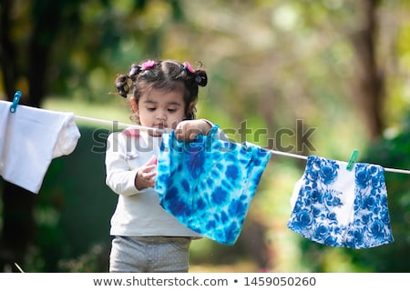 Foto d'archivio: Girl Putting Clothing On A Washing Line