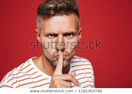 Stockfoto: Serious Man In Striped T Shirt Holding Index Finger On Lips With