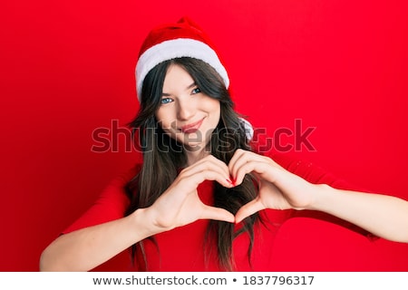 [[stock_photo]]: Young Beautiful Woman Wearing Christmas Hat Showing Heart Shape