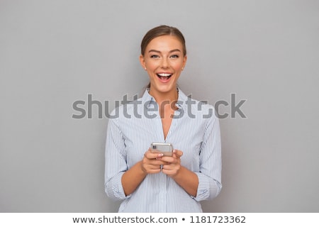 Stockfoto: Smiling Business Woman Standing Over Grey Wall Background Using Mobile Phone