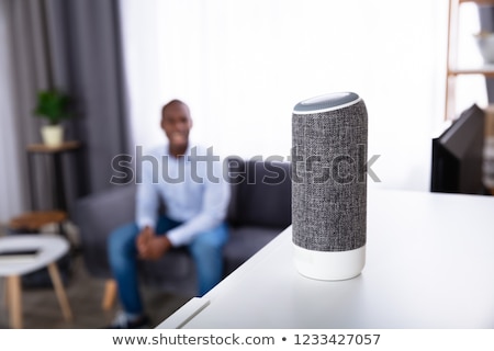 Stockfoto: Man Listening To Wireless Speaker On Furniture