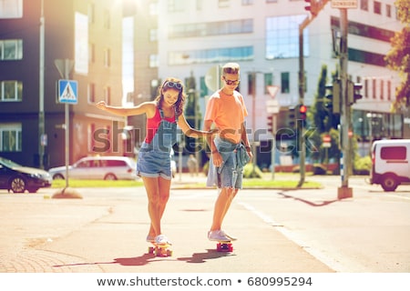 Stok fotoğraf: Teenage Couple Riding Skateboards On City Street