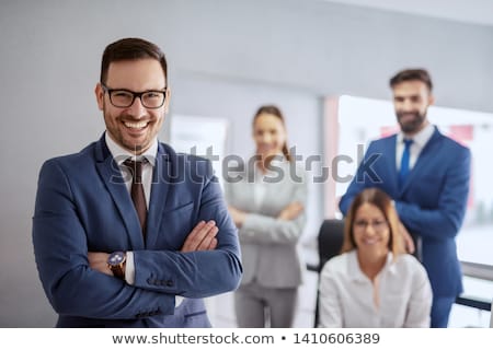 Stockfoto: Team Leader Stands With Colleagues In Background