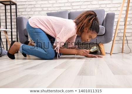 Сток-фото: Woman Looking At Hardwood Floor Through Magnifying Glass