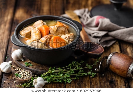 Stockfoto: Meat Stewed With Carrots In Sauce And Spices In Cast Iron Pot On Dark Wooden Rustic Background