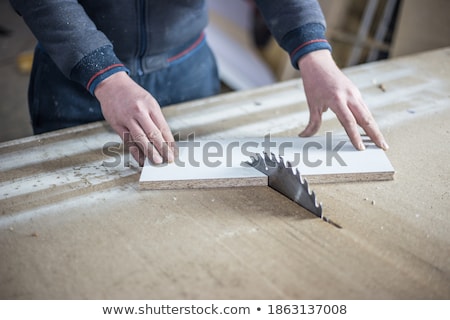 Stockfoto: Carpenter Cutting Wooden Board With Circular Saw