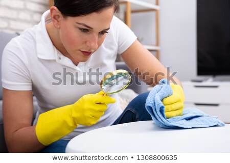 Foto stock: Female Janitor Examine Table Using Magnifying Glass