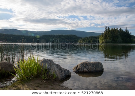 Foto stock: Mountain Lake With Rocks In Foreground At Sunset