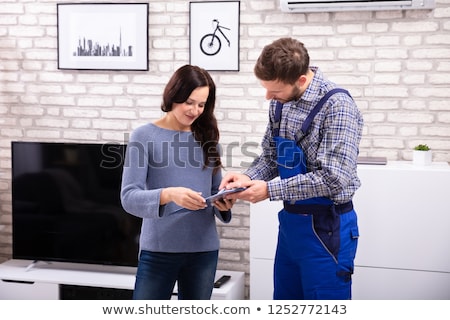 Foto d'archivio: Technician Assisting Woman In Signing Invoice