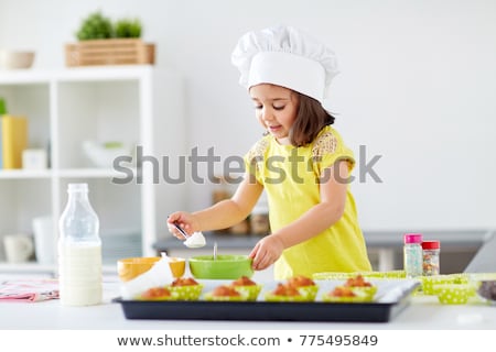 Stock fotó: Little Girl In Chefs Toque Baking Muffins At Home