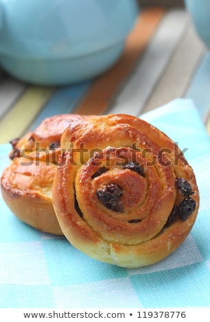 Stock fotó: Fresh Sweet Swirl Buns With Raisins On Colored Wooden Table