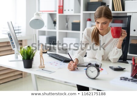 [[stock_photo]]: A Young Girl Is Sitting At A Computer Desk Holding A Pencil In Her Hand And Working With Documents