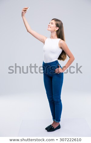Stockfoto: Full Length Portrait Of A Joyful Young Woman Taking Selfie