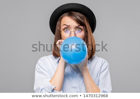 Brunette Girl In Hat And Eyeglasses Blowing Blue Balloon For Party Stockfoto © Pressmaster