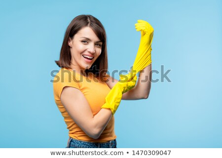 Foto d'archivio: Young Housekeeper Putting On Yellow Rubber Gloves Before Housework