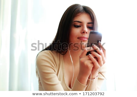 [[stock_photo]]: Thoughtul Attractive Woman Listening To Music From Smartphone