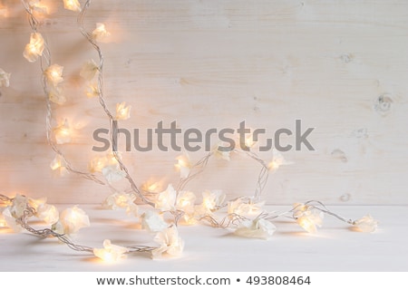Foto stock: Christmas Lights Burning On A White Wooden Background