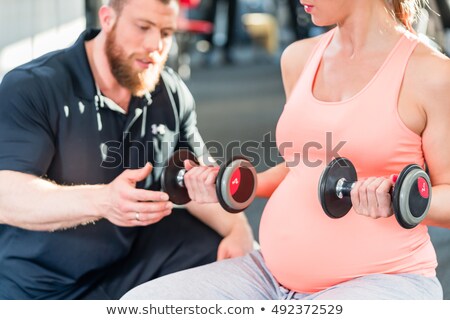 Stok fotoğraf: Pregnant Woman Working Out With Dumbbells With Personal Trainer At The Gym