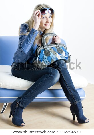 Stockfoto: Woman Wearing Blue Clothes With Handbag Sitting On Sofa