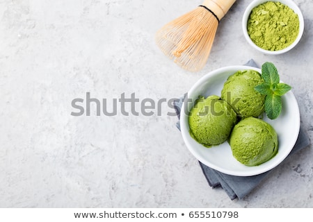Foto d'archivio: Green Tea Matcha Ice Cream Scoop In White Bowl On A Grey Stone Background Copy Space Top View