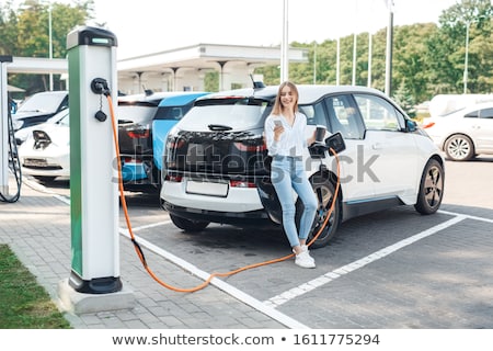 Сток-фото: Young Woman Leaning On Electric Car