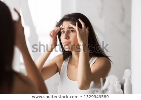 Stock photo: Woman Looking In Mirror Squeezing Pimple