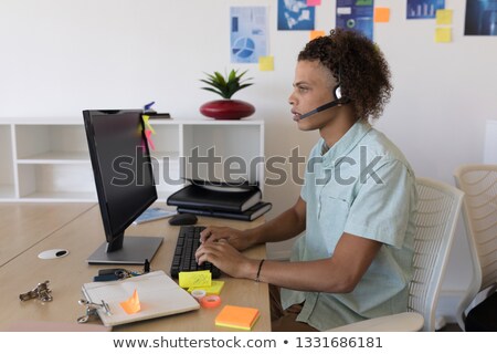 Stock fotó: Side View Of Mixed Race Male Executive In Headset Working At Desk In Office