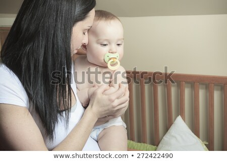 Foto stock: Devoted Mother Laying Son Down Into Crib For Nap In Bedroom