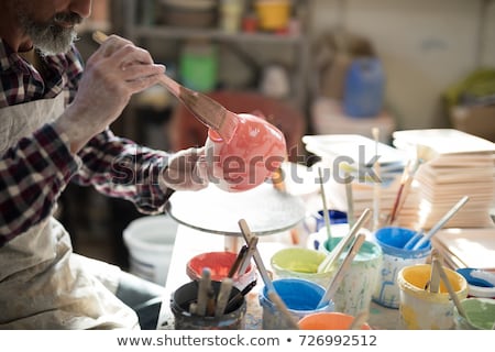 Stockfoto: Male Potters Painting A Bowl In Pottery Workshop