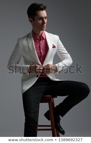 Stockfoto: Seated Businessman Buttoning His Suit And Looking To Side