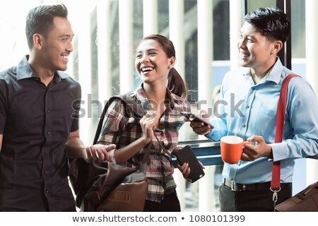 Three Young And Cheerful Employees Talking In The Morning Foto stock © Kzenon