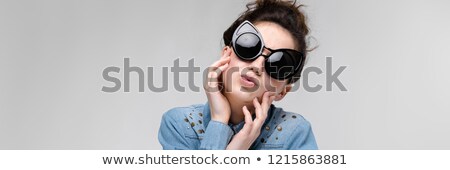 Stock photo: Young Brunette Girl In Black Glasses Cat Glasses The Hair Is Gathered In A Bun The Girl Is Holdin