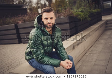 Stok fotoğraf: Attractive Man Dressed In Coat Sitting At The City Street