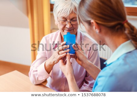 Stockfoto: Caregiver Helping Senior Woman Drinking Giving Her A Cup Of Water